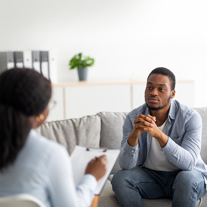 man talking to a mental health counselor on a sofa